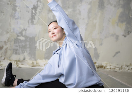 一位女士正在為舞蹈或運動熱身，伸展手臂和腿，雙腿分開向前彎曲 126391186