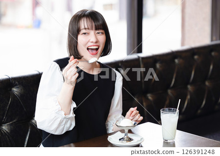 Woman eating ice cream in a cafe Woman eating ice cream in a cafe 126391248