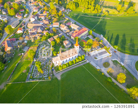 Set in the village of Bohutin, the Church of Saint Mary Magdalene stands surrounded by lush greenery and quaint houses. This serene location features a nearby cemetery and well-maintained landscapes. 126391891