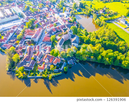 Overlooking the charming town of Rozmital pod Tremsinem, this vibrant area features a historic castle surrounded by lush greenery and tranquil waters, showcasing local life. 126391906