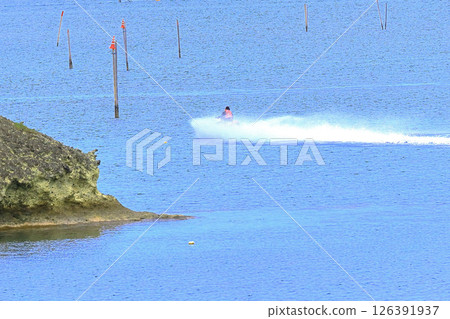 A motorboat raising a cloud of water at breakneck speed 126391937