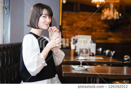 A woman drinking juice at a cafe 126392012