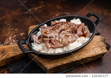 Exquisite Japanese BBQ, highlighting beautifully charred meats and rice. Perfectly seasoned, this dish promises a rich and savory flavor in every bite. brown background. top view Exquisite Japanese BBQ, highlighting beautifully charred meats and rice. Perfectly seasoned, this dish promises a rich and savory flavor in every bite. brown background. top view 126392177