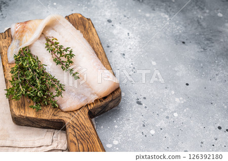 Fresh cod fish fillet, showcasing its delicate texture and pristine color, perfect for grilling or baking. grey background. top view 126392180