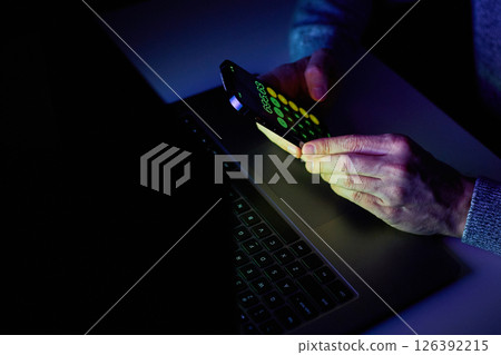 Male hands are using calculator on mobile phone and laptop keyboard. 126392215