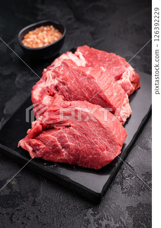 Raw beef boneless shank shin presented with herbs and spices, inspiring bold flavors and unique recipes for adventurous home cooks. black background. top view Raw beef boneless shank shin presented with herbs and spices, inspiring bold flavors and unique recipes for adventurous home cooks. black background. top view 126392229