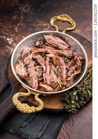 Close-up of succulent pulled brisket piled high on a rustic wooden board, garnished with fresh herbs, delicious meal. brown background. top view Close-up of succulent pulled brisket piled high on a rustic wooden board, garnished with fresh herbs, delicious meal. brown background. top view 126392259