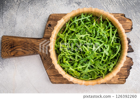 Fresh arugula leaves, vibrant and peppery, perfect for adding a zesty touch to salads and sandwiches. grey background. top view Fresh arugula leaves, vibrant and peppery, perfect for adding a zesty touch to salads and sandwiches. grey background. top view 126392260