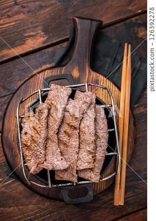 Flavorful yakiniku with juicy wagyu beef slices cooked right at the table. wooden background. top view 126392278