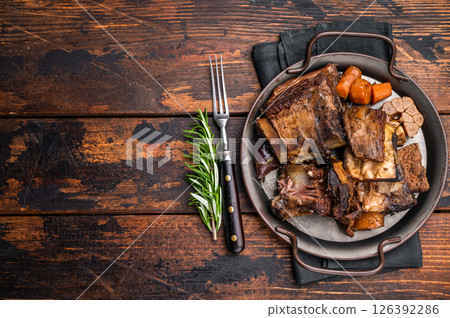 Grilled beef short ribs glistening under natural light, accompanied by fresh greens and spices, capturing the essence of gourmet comfort food. wooden background. top view 126392286