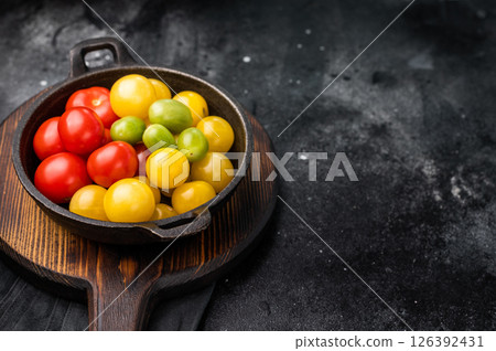 Uncooked small tomatoes. red, green and yellow cherry tomatoes assortment, cocktail mix. black background. top view 126392431