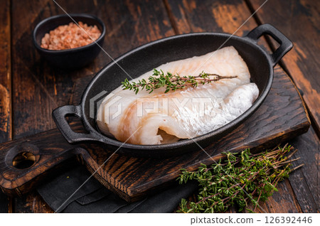 Pristine raw cod fillet, waiting to be marinated and cooked to perfection for a delightful dining experience. wooden background. top view Pristine raw cod fillet, waiting to be marinated and cooked to perfection for a delightful dining experience. wooden background. top view 126392446