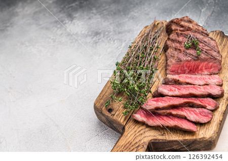 Flavorsome beef Denver shoulder tender, grilled in BBQ to juicy perfection, served with fresh herbs. grey background. top view Flavorsome beef Denver shoulder tender, grilled in BBQ to juicy perfection, served with fresh herbs. grey background. top view 126392454