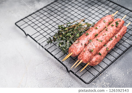 Raw kofta or lula kebabs skewers from mince lamb and beef meat on Skewer. grey background. top view Raw kofta or lula kebabs skewers from mince lamb and beef meat on Skewer. grey background. top view 126392543
