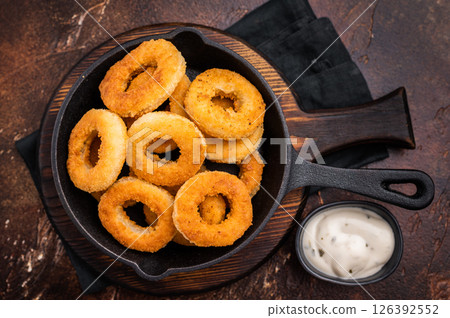 Crispy Fried onion rings, delicious snack in a pan. brown background. top view Crispy Fried onion rings, delicious snack in a pan. brown background. top view 126392552