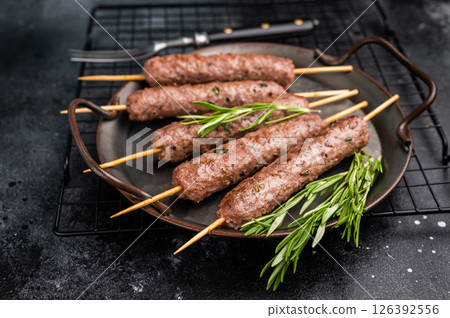 Grilled minced beef and lamb kebabs skewers with fresh spices, arabic kofta kofte kebab. black background. top view Grilled minced beef and lamb kebabs skewers with fresh spices, arabic kofta kofte kebab. black background. top view 126392556