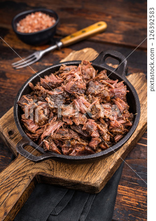 Traditional Barbecue smoked beef meat, pulled beef in a skillet. wooden background. top view Traditional Barbecue smoked beef meat, pulled beef in a skillet. wooden background. top view 126392583