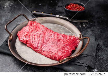 Uncooked flank steak, raw beef flap meat steak. black background. top view Uncooked flank steak, raw beef flap meat steak. black background. top view 126392614