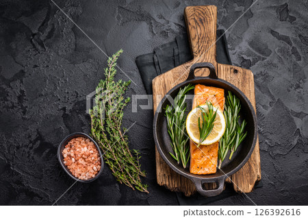 Fried salmon fillet with herbs, grilled fish steak in a pan. black background. top view 126392616