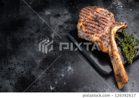 BBQ Grilled Tomahawk beef steak, cooked rib eye with bone on marble board. black background. top view 126392617