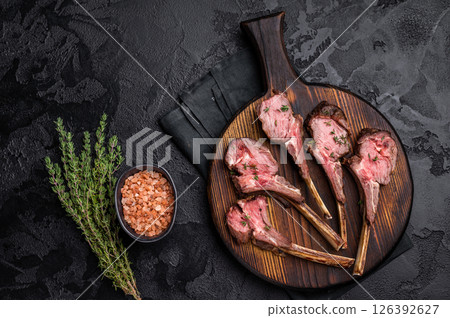 French roast lamb chops, mutton meat steaks on wooden board. black background. top view French roast lamb chops, mutton meat steaks on wooden board. black background. top view 126392627