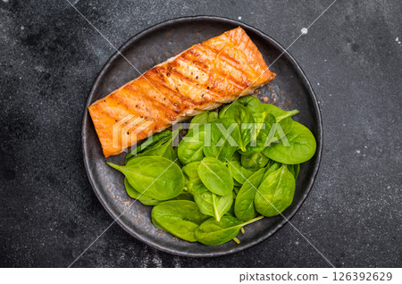 Roast salmon fillet steak with spinach. black background. top view Roast salmon fillet steak with spinach. black background. top view 126392629