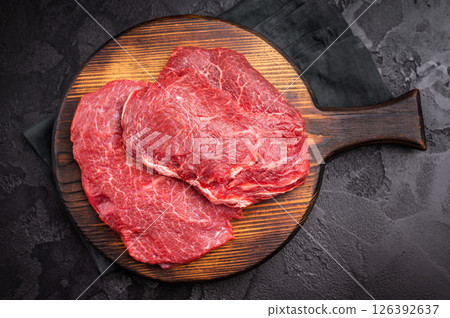 Butcher board with raw beef cheeks, uncooked meat. black background. top view Butcher board with raw beef cheeks, uncooked meat. black background. top view 126392637