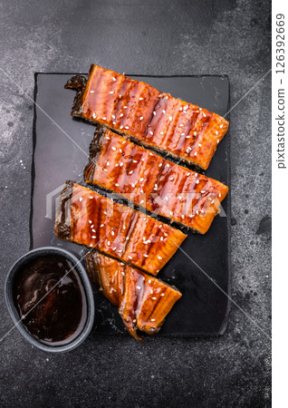 Unagi kabayaki eel, japanese grilled fish fillet with sauce. black background. top view Unagi kabayaki eel, japanese grilled fish fillet with sauce. black background. top view 126392669