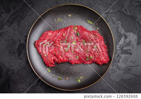 Marinated Flank or Flap steak, raw beef meat with thyme and spices on plate. black background. top view 126392688