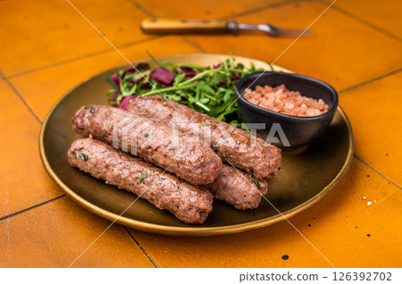 Grilled kofta or lula kebabs from mince lamb and beef meat on a plate with salad. brown background. top view Grilled kofta or lula kebabs from mince lamb and beef meat on a plate with salad. brown background. top view 126392702