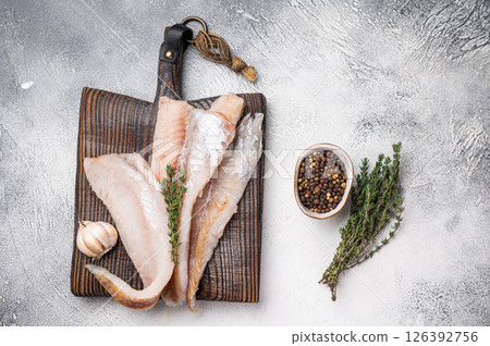 fresh Raw Pollock fish fillets on a wooden board with herbs. white background. top view 126392756