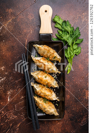 Fried Korean Dumplings on plate with sauce, Dumplings with shrimps and vegetables. brown background. top view Fried Korean Dumplings on plate with sauce, Dumplings with shrimps and vegetables. brown background. top view 126392762