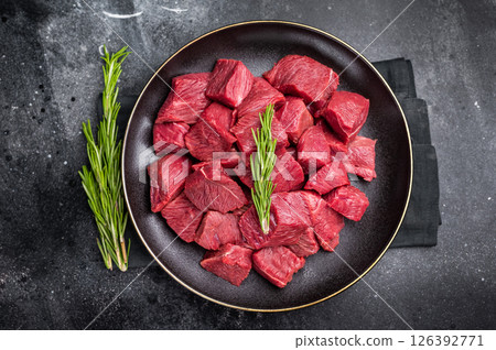 Diced Raw Boar meat, fresh Game Meat in a plate. black background. top view Diced Raw Boar meat, fresh Game Meat in a plate. black background. top view 126392771