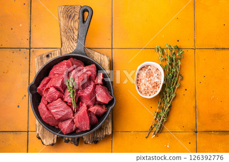 Ready for cooking Diced Elk meat, raw Game Meat in a pan. orange background. top view Ready for cooking Diced Elk meat, raw Game Meat in a pan. orange background. top view 126392776