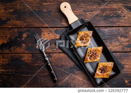 Homemade Walnut Baklava with honey on plate. wooden background. top view Homemade Walnut Baklava with honey on plate. wooden background. top view 126392777