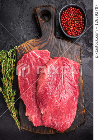 Raw Boar meat steak, uncooked Game Meat on cutting board. black background. top view 126392787
