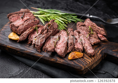 Roast Skirt Machete Steak, grilled beef meat on cutting board. black background. top view 126392878
