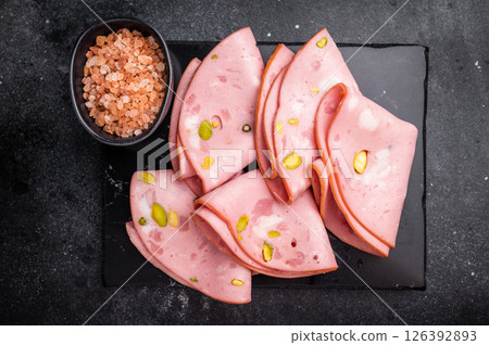 Mortadella Bolognese sausage slices with pistachios. black background. top view 126392893