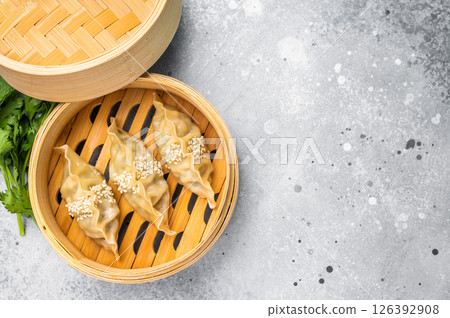 Steamed Japanese Gyoza Dumplings with pork meat and vegetables in bamboo steamer. grey background. top view 126392908