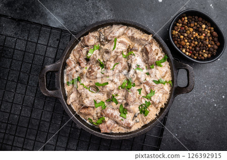 Creamy beef stroganoff with fresh greenery in a skillet. black background. top view Creamy beef stroganoff with fresh greenery in a skillet. black background. top view 126392915