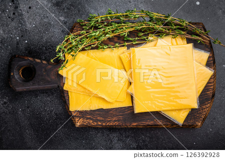 Fresh Processed Melted cheese, thin slices for toasts. black background. top view 126392928