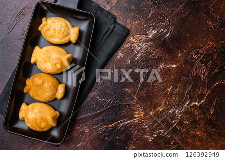Japanese Taiyaki Fish Shaped Waffle with Sweet Paste. brown background. top view Japanese Taiyaki Fish Shaped Waffle with Sweet Paste. brown background. top view 126392949