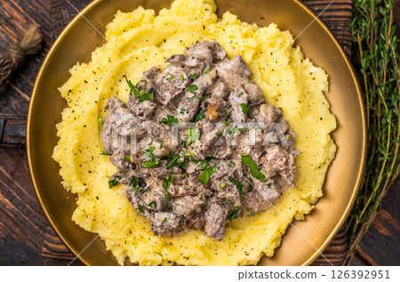 Beef Stroganoff over mashed potatoes with creamy sauce in a plate. wooden background. top view Beef Stroganoff over mashed potatoes with creamy sauce in a plate. wooden background. top view 126392951