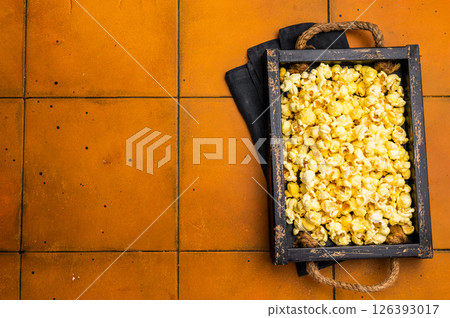 Cheese and salty popcorn in wooden tray. orange background. top view 126393017