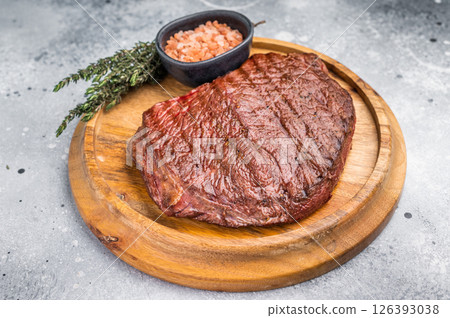 Perfectly grilled top sirloin steak, seared to a juicy finish and garnished with fresh herbs for an irresistible flavor. grey background. top view 126393038