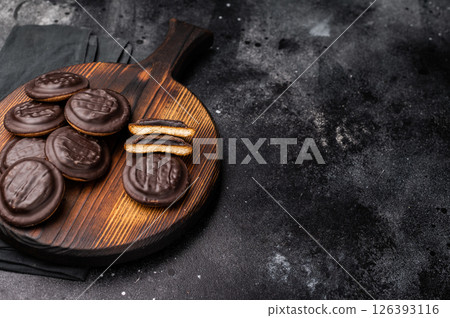 Jaffa Cookies covered with chocolate and filled with jam on wooden board. black background. top view 126393116