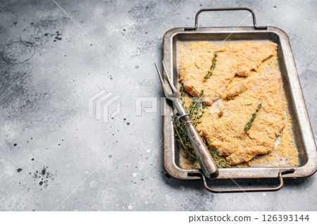 Cooking of Raw breaded Wiener Schnitzel steak in steel tray. gray background. top view 126393144