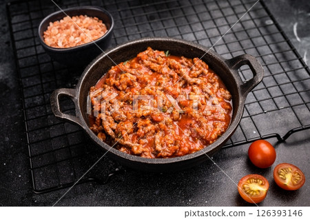 Bolognese sauce with minced beef, tomato paste and herbs in a skillet. black background. top view Bolognese sauce with minced beef, tomato paste and herbs in a skillet. black background. top view 126393146