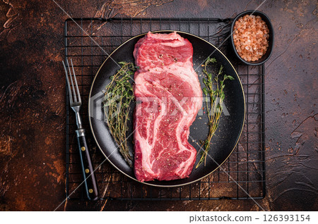 Chuck eye roll steak, raw marbled beef meat with herb for cooking. brown background. top view Chuck eye roll steak, raw marbled beef meat with herb for cooking. brown background. top view 126393154