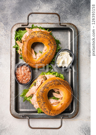 Fresh healthy bagel sandwich with smoked salmon, lettuce and cream cheese on a tray. gray background. top view 126393158